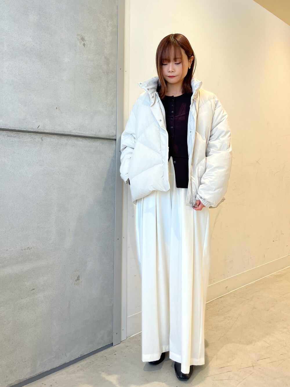 ホワイト系のダウンジャケット/コート、ブラウン系のニット/セーター、ホワイト系のその他パンツを着用したレディースの冬コーディネートの2枚目の写真