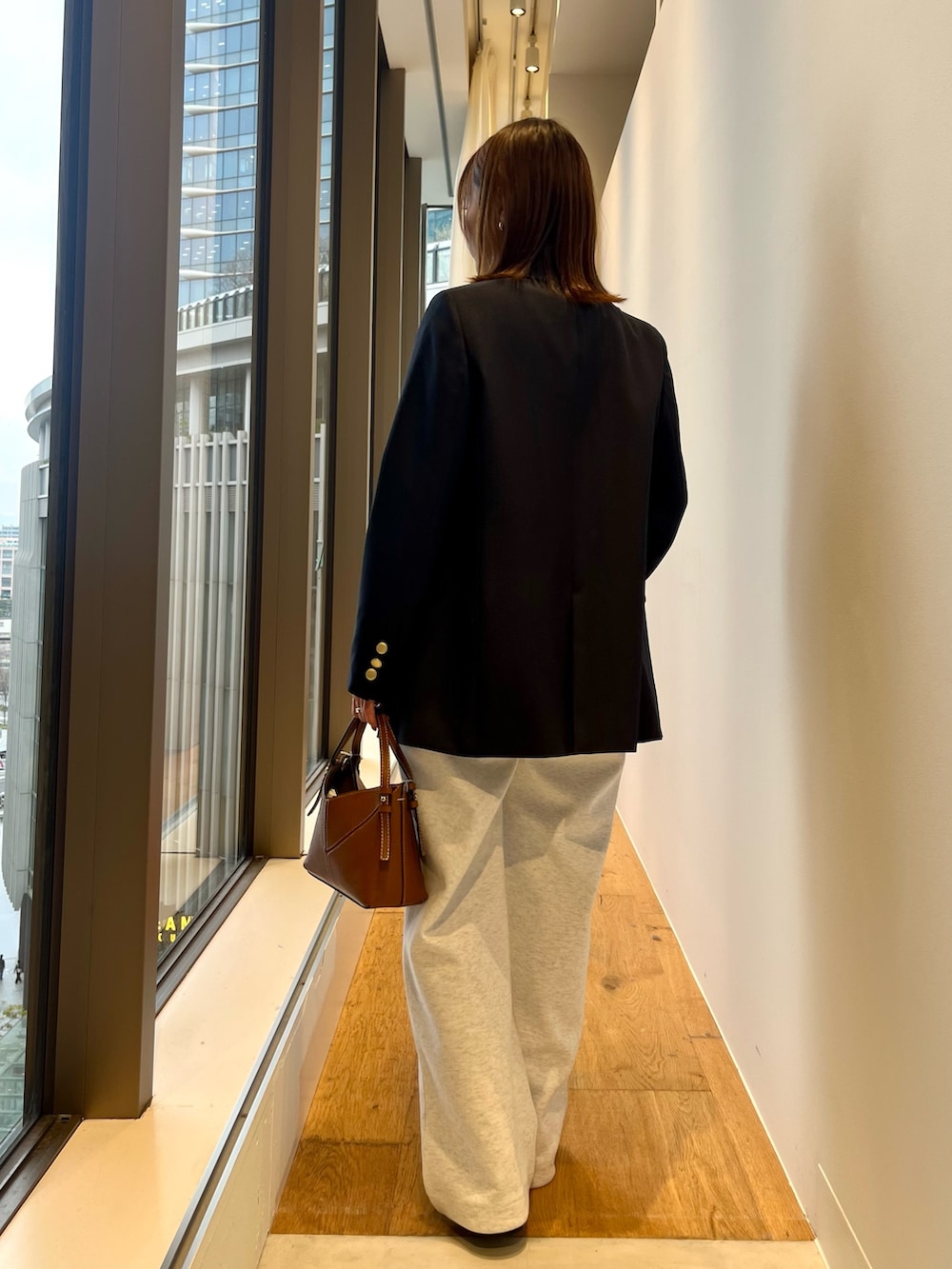 ブルー系のその他アウター、グレー系のその他パンツ、ブラウン系のハンドバッグを着用したレディースの春コーディネートの3枚目の写真