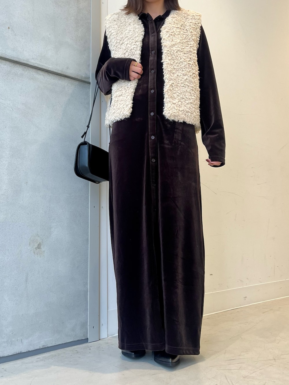 ホワイト系のベスト、ブラウン系のワンピース、ブラック系のショルダーバッグを着用したレディースの秋コーディネートの2枚目の写真