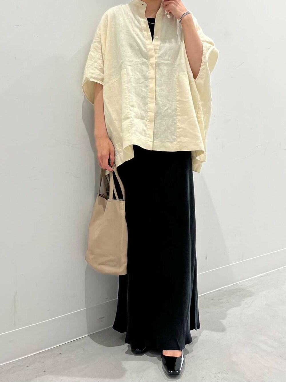 ブラック系のパンプス、ブラック系のスカート、イエロー系のシャツ/ブラウスを着用したレディースの春コーディネートの2枚目の写真