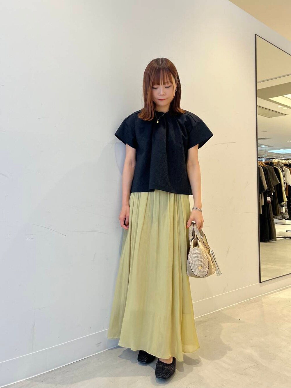 ベージュ系のかごバッグ、ブラック系のバレエシューズ、グリーン系のスカートを着用したレディースの春コーディネートの5枚目の写真