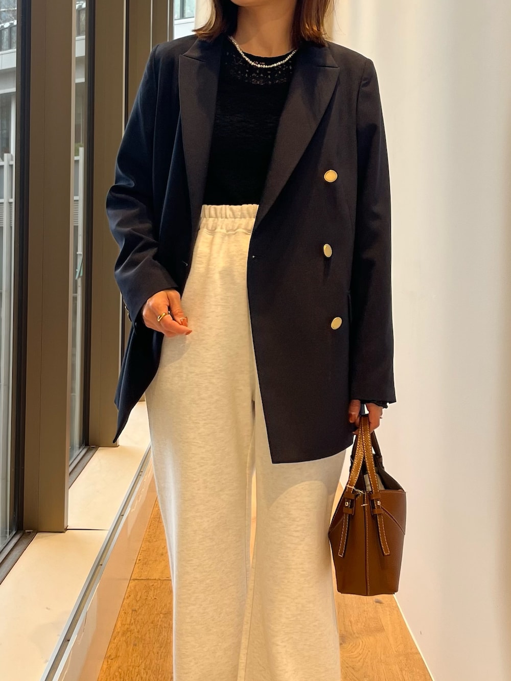 ブルー系のその他アウター、グレー系のその他パンツ、ブラウン系のハンドバッグを着用したレディースの春コーディネートの2枚目の写真