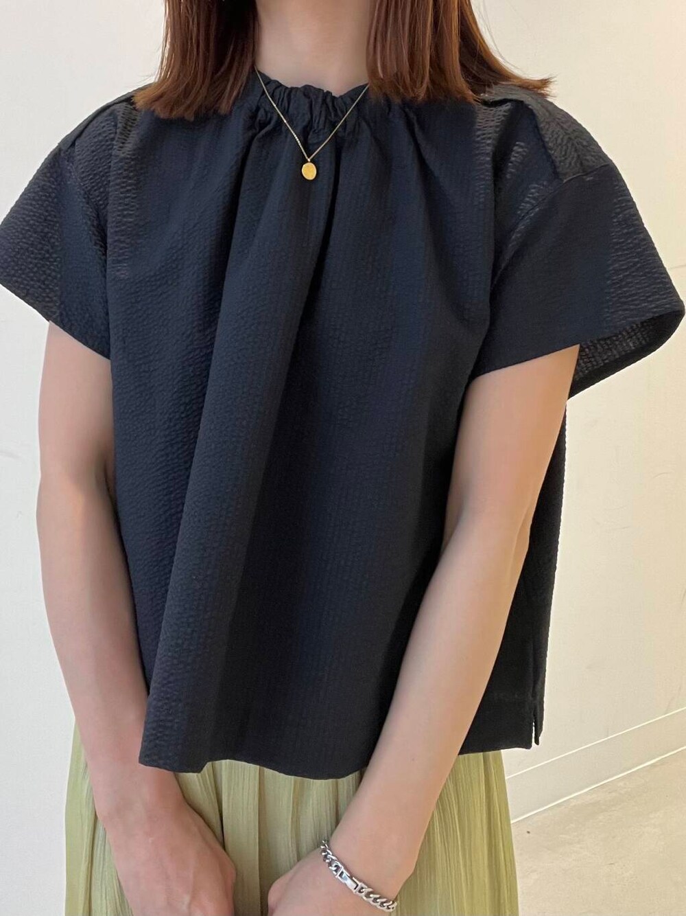 ベージュ系のかごバッグ、ブラック系のバレエシューズ、グリーン系のスカートを着用したレディースの春コーディネートの2枚目の写真