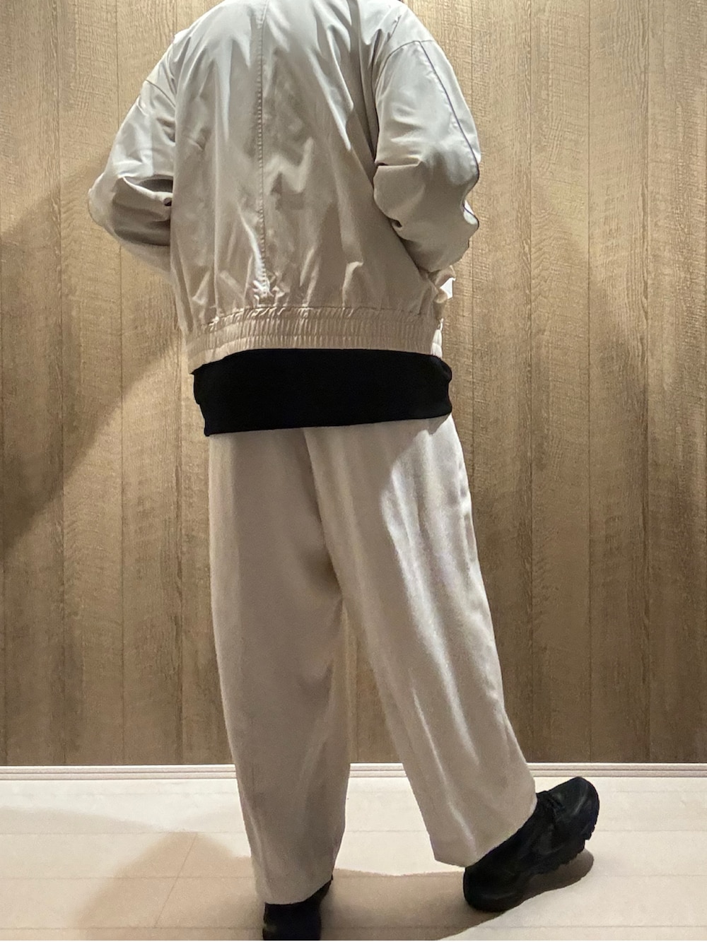 ホワイト系のブルゾン、ホワイト系のスラックス、ブラック系のスニーカーを着用したメンズの秋コーディネートの3枚目の写真