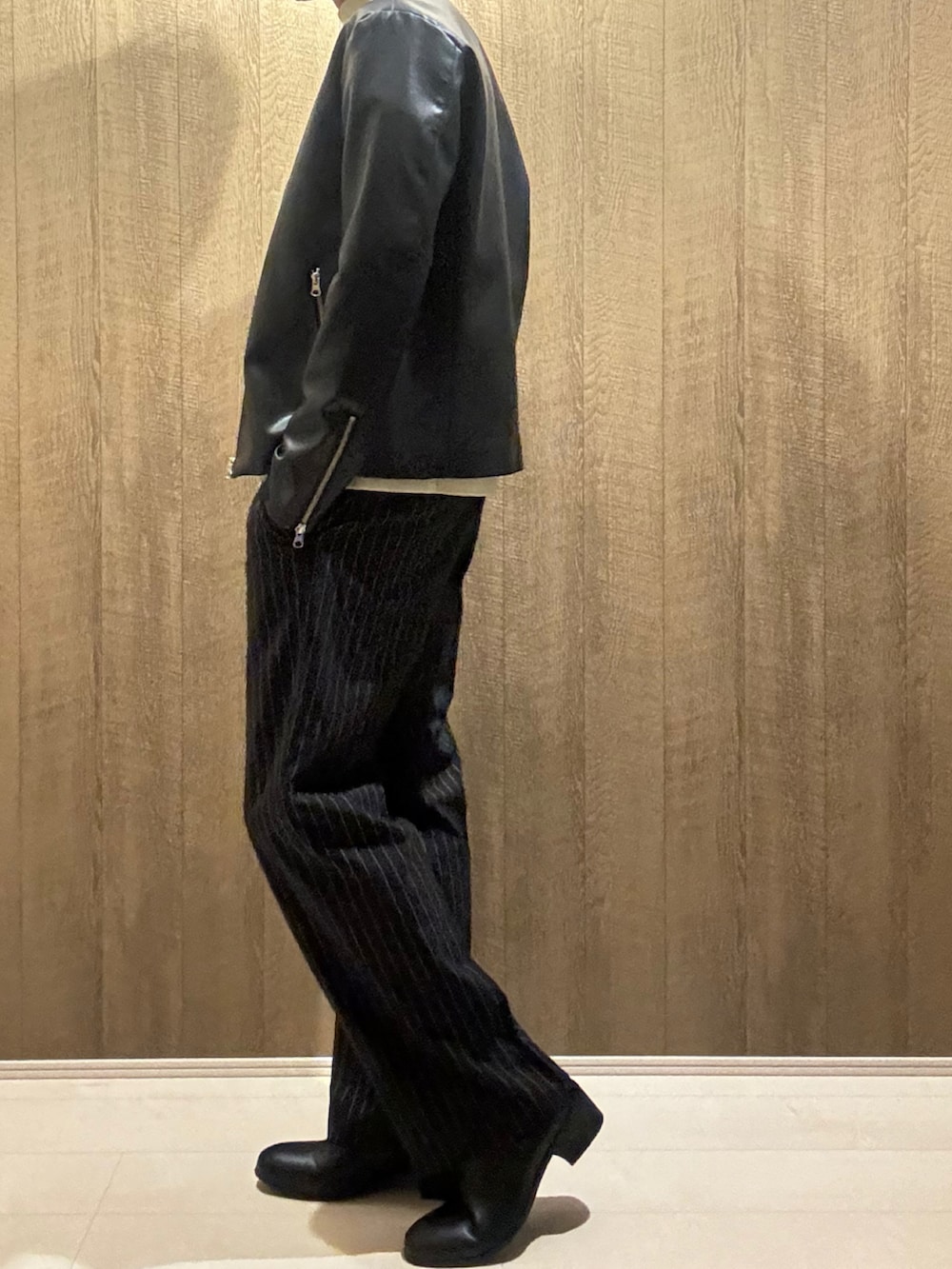 ブラック系のライダースジャケット、ホワイト系のニット/セーター、ブラック系のその他パンツを着用したメンズの秋コーディネートの2枚目の写真