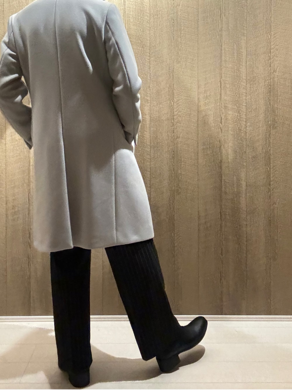 グレー系のチェスターコート、ブラック系のその他パンツ、ブラック系のブーツを着用したメンズの秋コーディネートの3枚目の写真