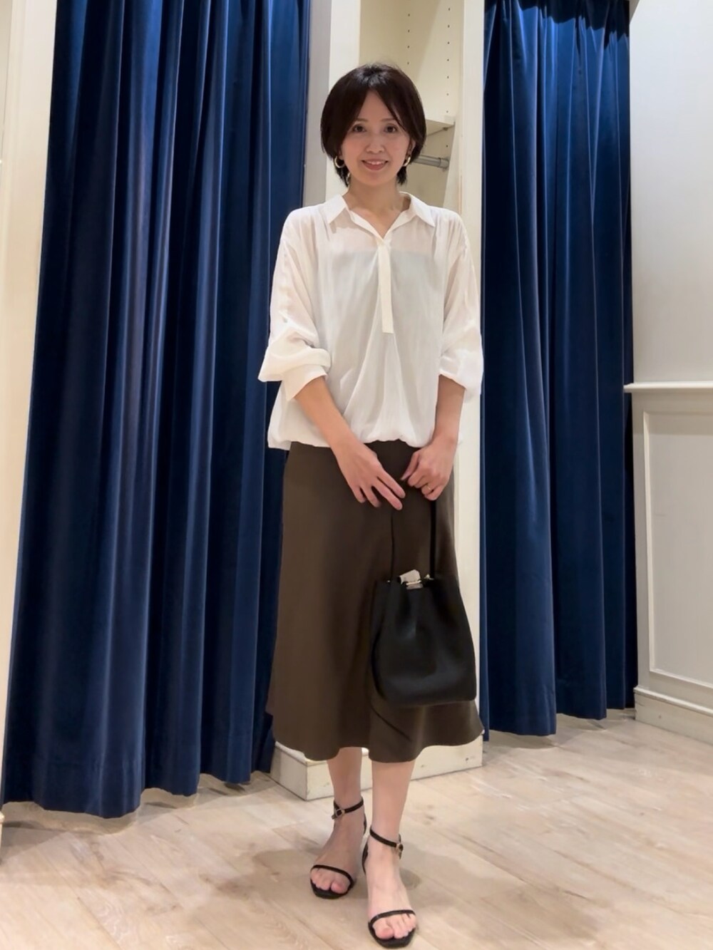 ホワイト系のシャツ/ブラウス、グリーン系のスカート、ブラック系のショルダーバッグを着用したレディースの秋コーディネートの2枚目の写真