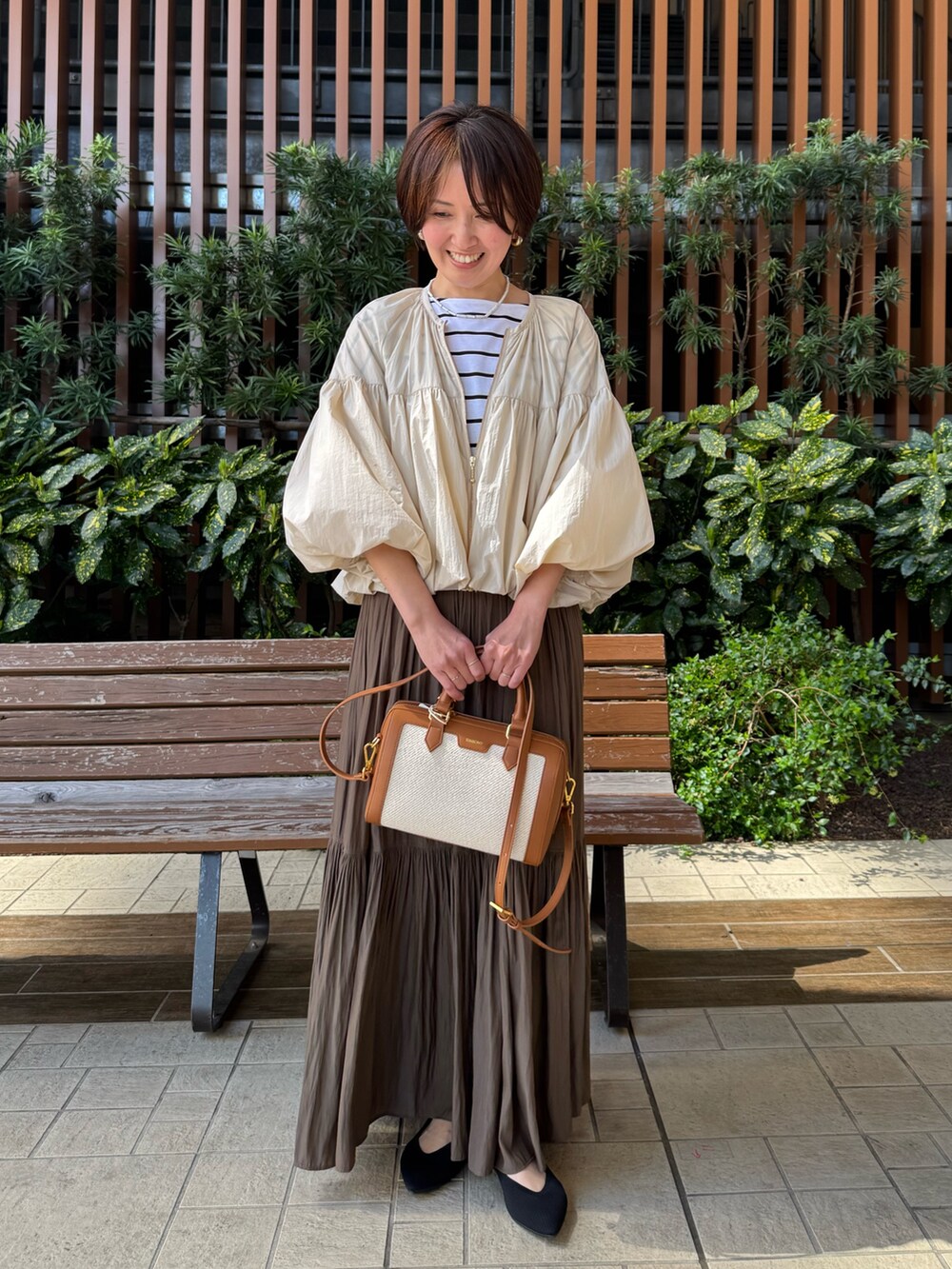 ホワイト系のTシャツ/カットソー、グリーン系のスカート、ブラウン系のボストンバッグを着用したレディースの春コーディネートの2枚目の写真