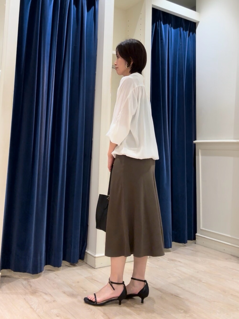 ホワイト系のシャツ/ブラウス、グリーン系のスカート、ブラック系のショルダーバッグを着用したレディースの秋コーディネートの3枚目の写真