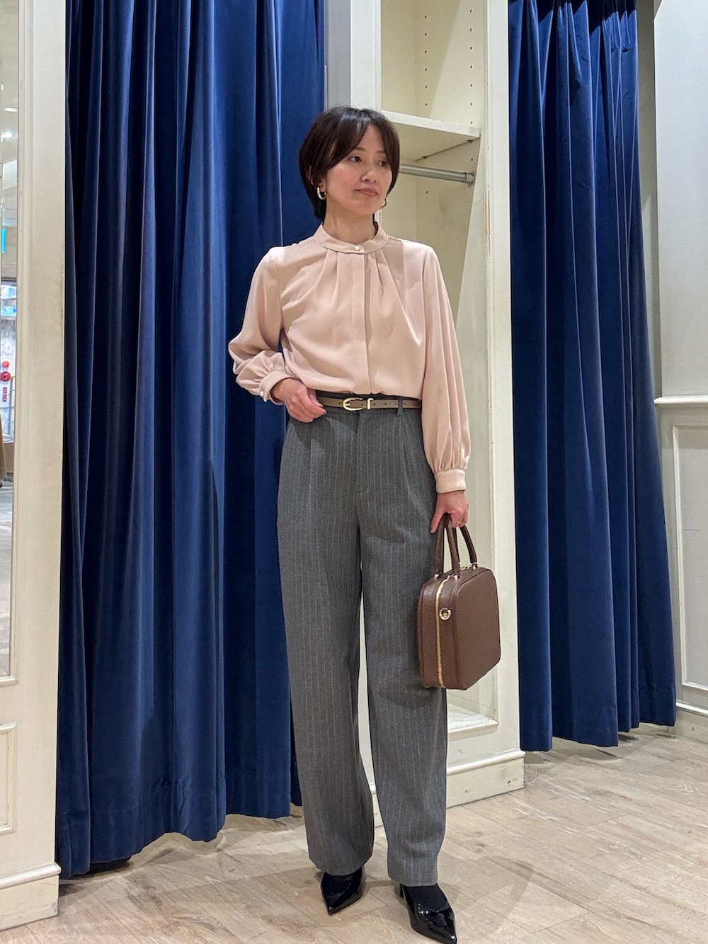 ピンク系のシャツ/ブラウス、グレー系のその他パンツ、ブラウン系のボストンバッグを着用したレディースの冬コーディネートの2枚目の写真