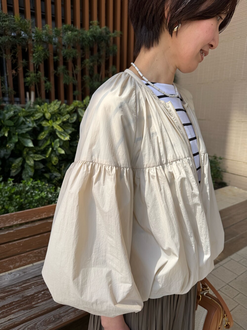 ホワイト系のTシャツ/カットソー、グリーン系のスカート、ブラウン系のボストンバッグを着用したレディースの春コーディネートの6枚目の写真