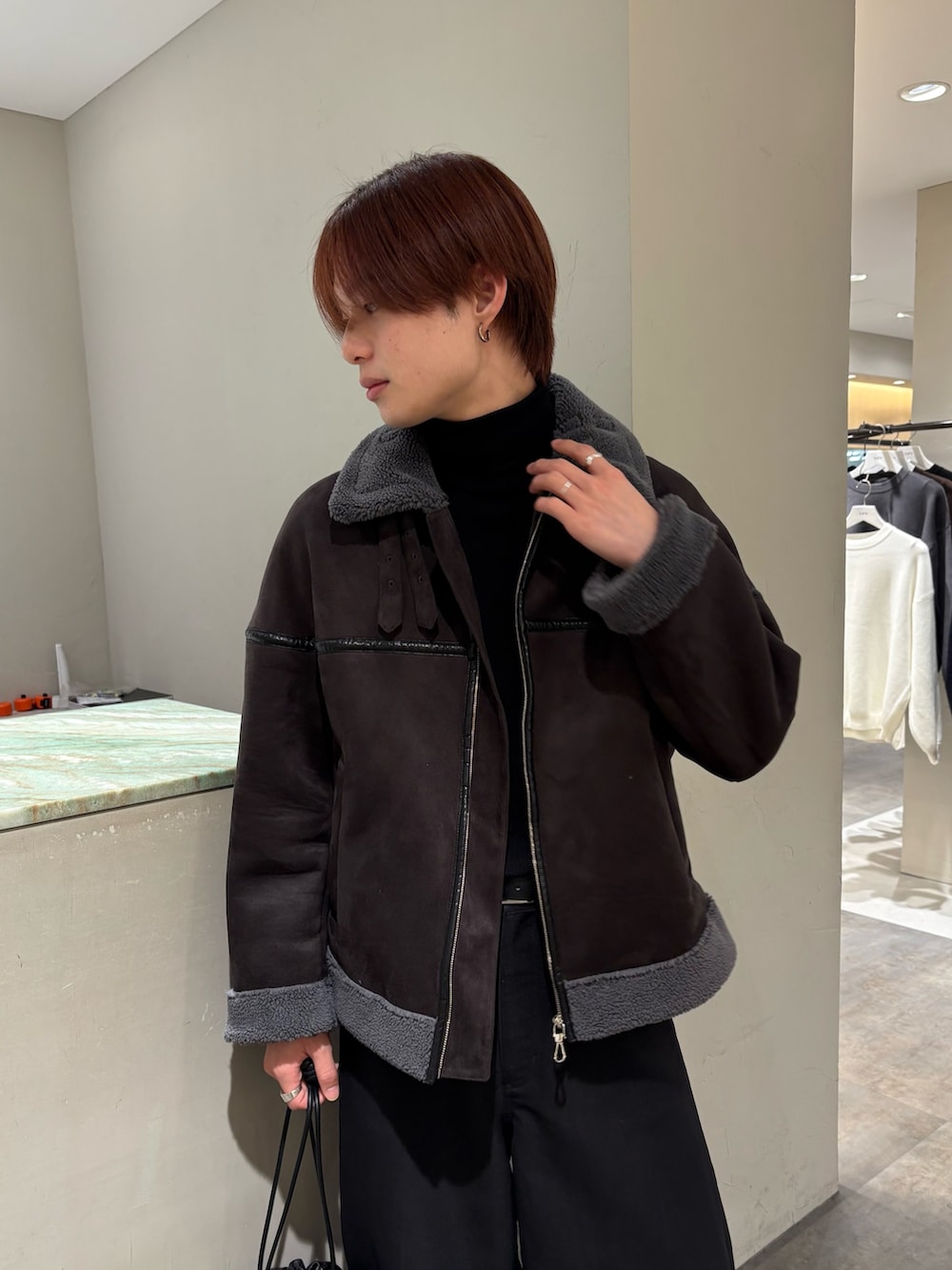 グレー系のブルゾン、ブラック系のスラックス、ブラック系のローファーを着用したメンズの冬コーディネートの2枚目の写真