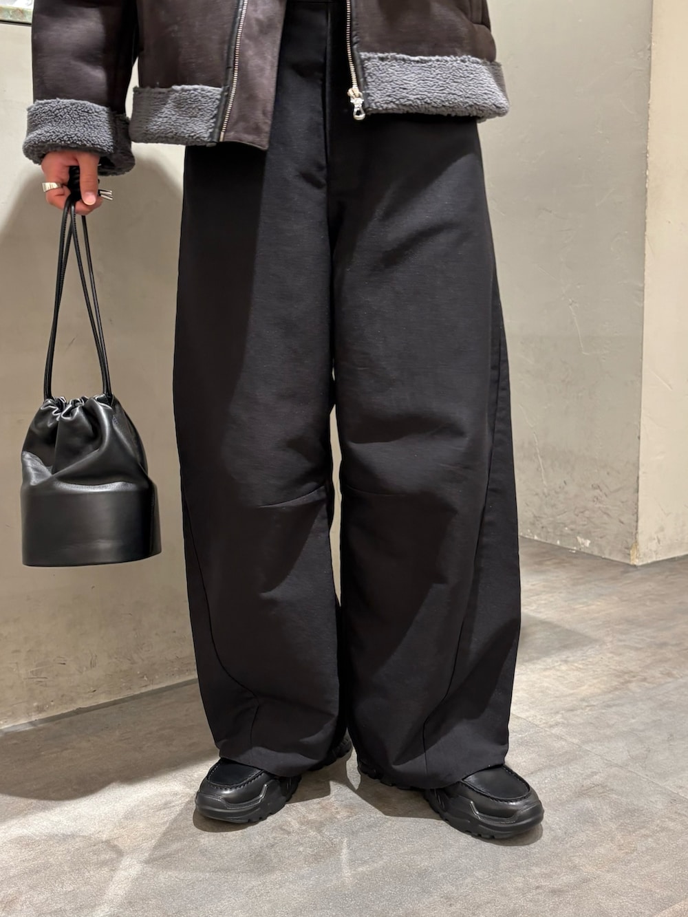 グレー系のブルゾン、ブラック系のスラックス、ブラック系のローファーを着用したメンズの冬コーディネートの4枚目の写真