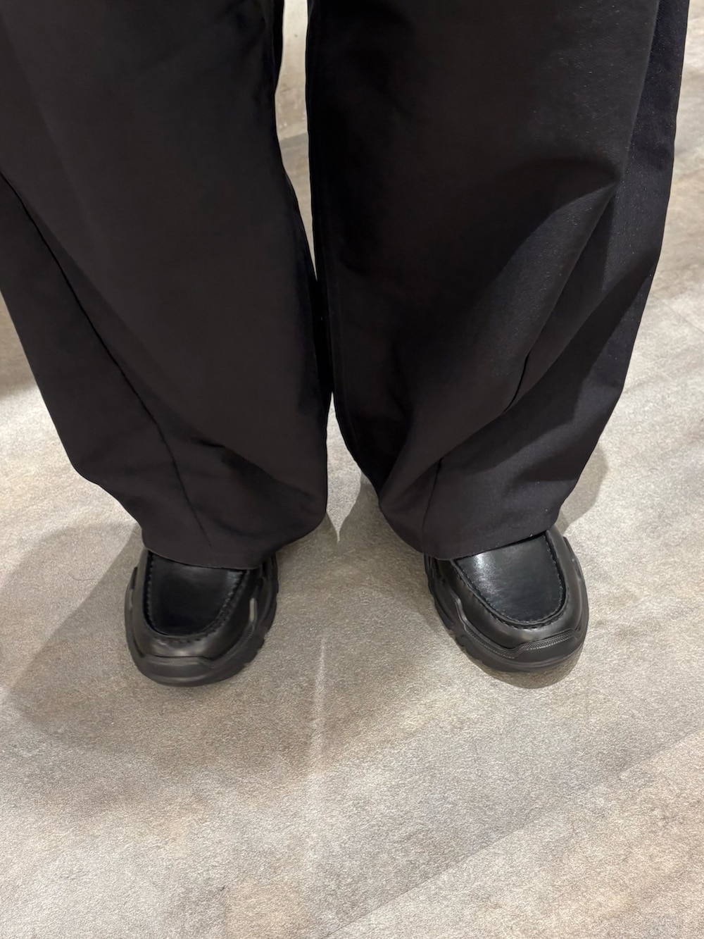 グレー系のブルゾン、ブラック系のスラックス、ブラック系のローファーを着用したメンズの冬コーディネートの5枚目の写真