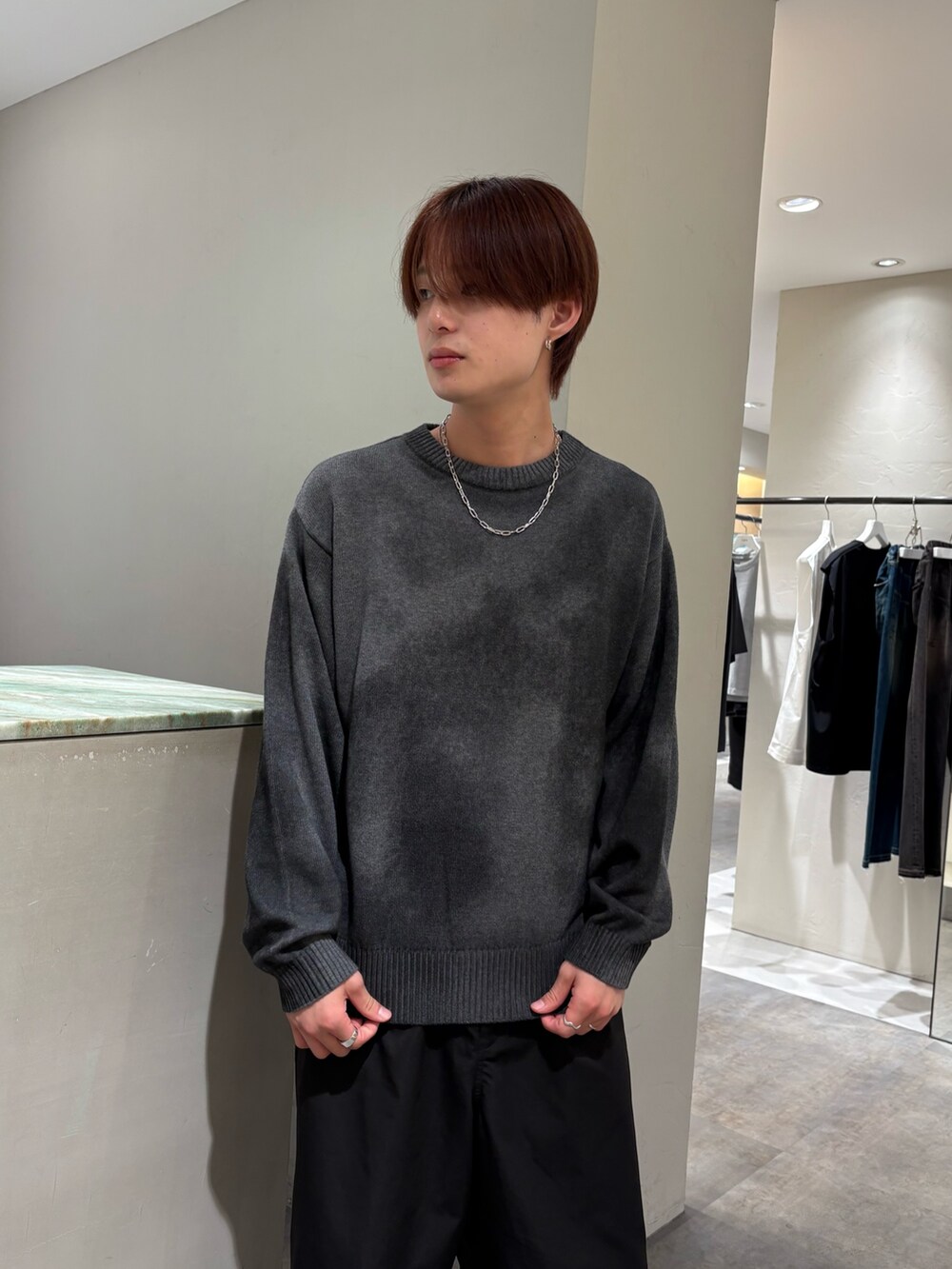 グレー系のニット/セーター、ブラック系のその他パンツ、シルバー系のネックレスを着用したメンズの秋コーディネートの4枚目の写真