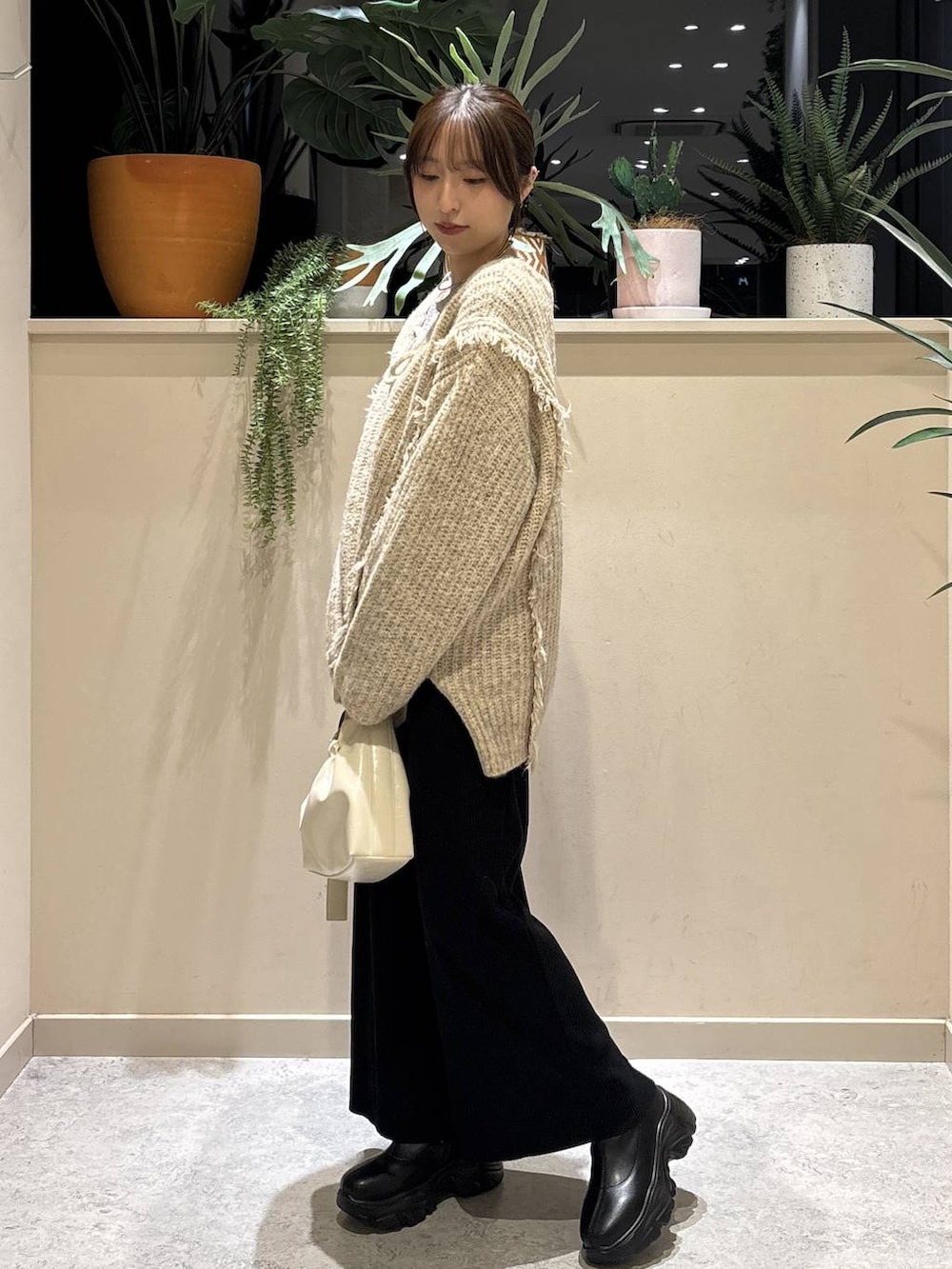 ブラック系のスカート、ホワイト系のTシャツ/カットソー、ブラック系のブーツを着用したレディースの冬コーディネートの2枚目の写真