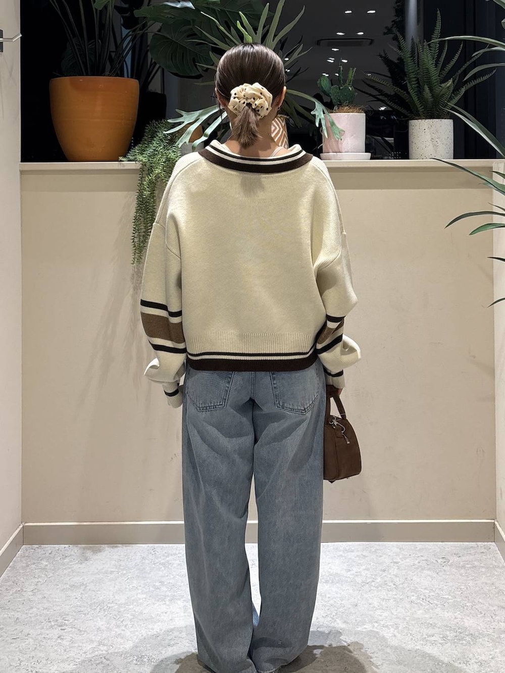 ブラウン系のボストンバッグ、ブルー系のデニムパンツ、ブラック系のパンプスを着用したレディースの冬コーディネートの3枚目の写真