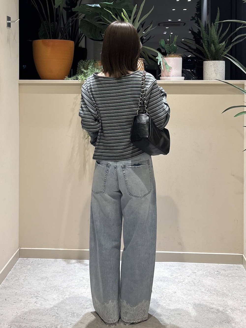 ブルー系のデニムパンツ、ブラック系のショルダーバッグ、ブラック系のスニーカーを着用したレディースの春コーディネートの3枚目の写真