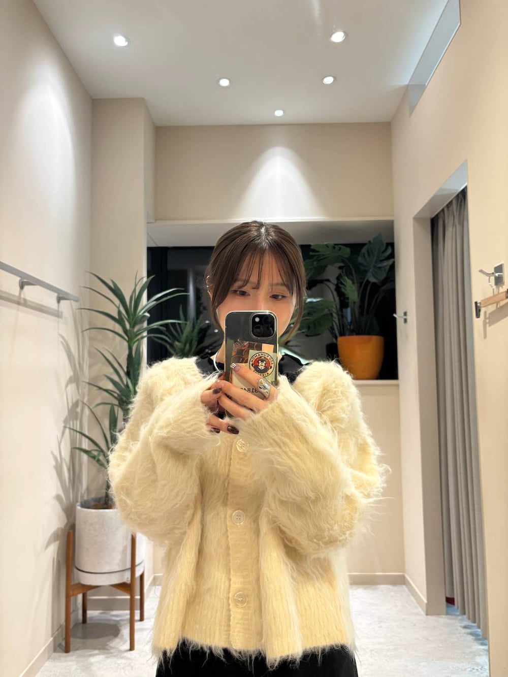 ブラック系のブーツ、ブラック系のスカート、ホワイト系のカーディガン/ボレロを着用したレディースの冬コーディネートの2枚目の写真