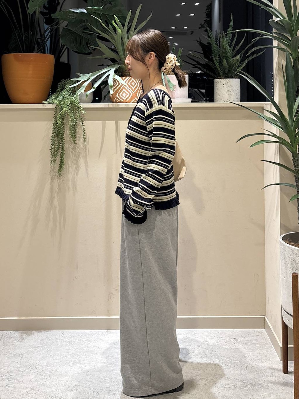 ブラック系のブーツ、ベージュ系のショルダーバッグ、グレー系のスウェットパンツを着用したレディースの冬コーディネートの2枚目の写真