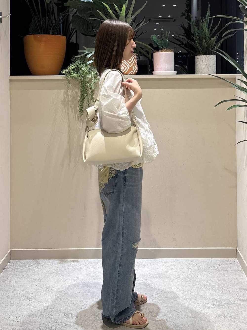 ブルー系のデニムパンツ、ホワイト系のサンダル、ホワイト系のシャツ/ブラウスを着用したレディースの夏コーディネートの4枚目の写真