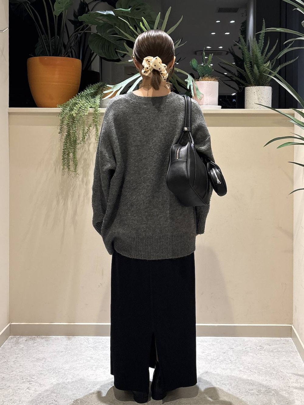 ブラック系のスカート、ブラック系のブーツ、ブラック系のボストンバッグを着用したレディースの冬コーディネートの3枚目の写真