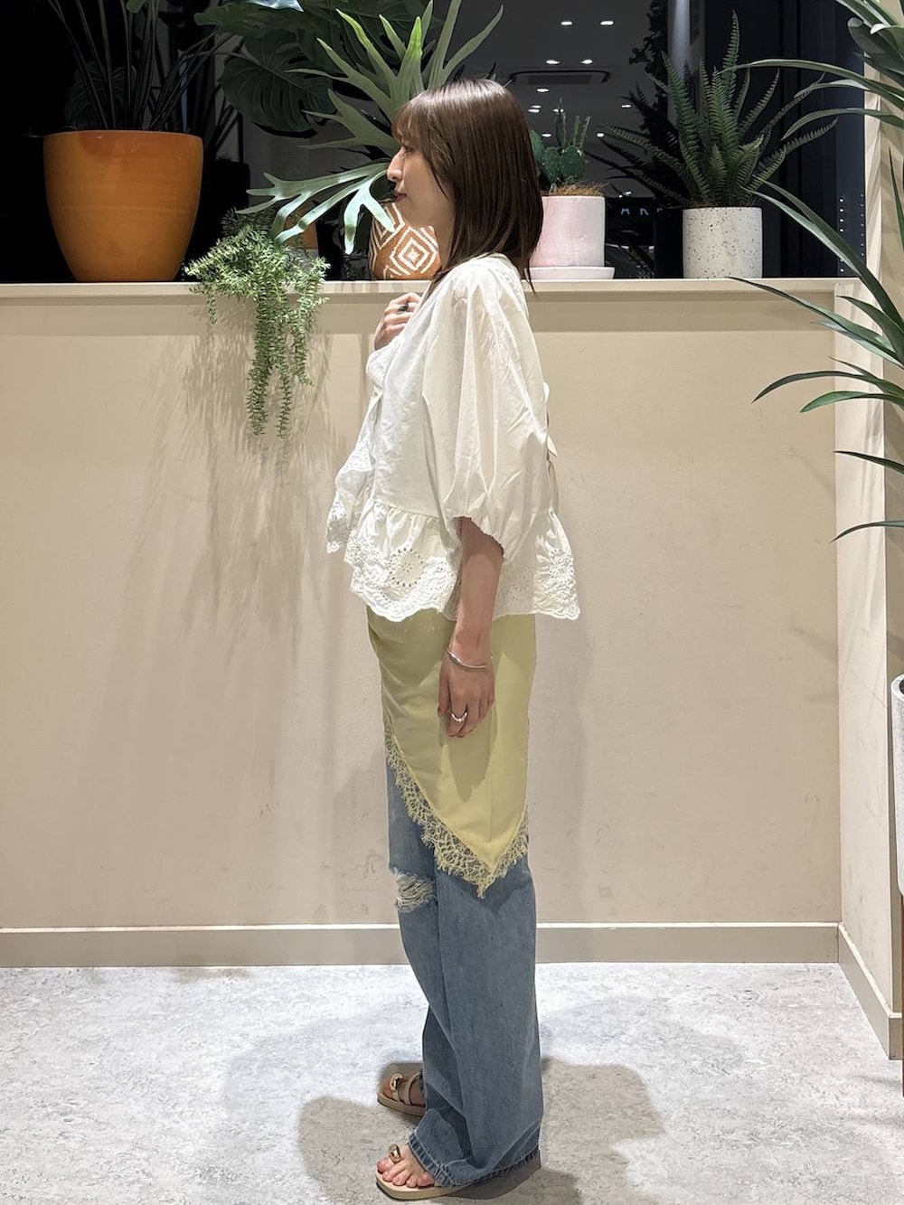 ブルー系のデニムパンツ、ホワイト系のサンダル、ホワイト系のシャツ/ブラウスを着用したレディースの夏コーディネートの2枚目の写真