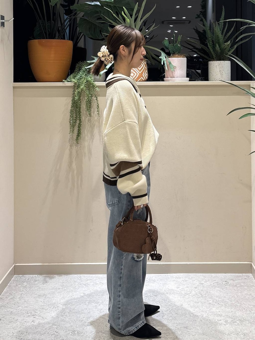 ブラウン系のボストンバッグ、ブルー系のデニムパンツ、ブラック系のパンプスを着用したレディースの冬コーディネートの4枚目の写真