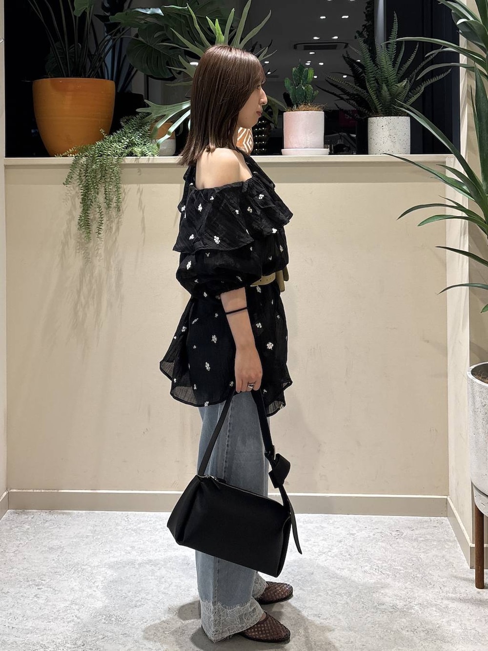 ブラック系のワンピース、ブルー系のデニムパンツ、ブラック系のショルダーバッグを着用したレディースの夏コーディネートの4枚目の写真