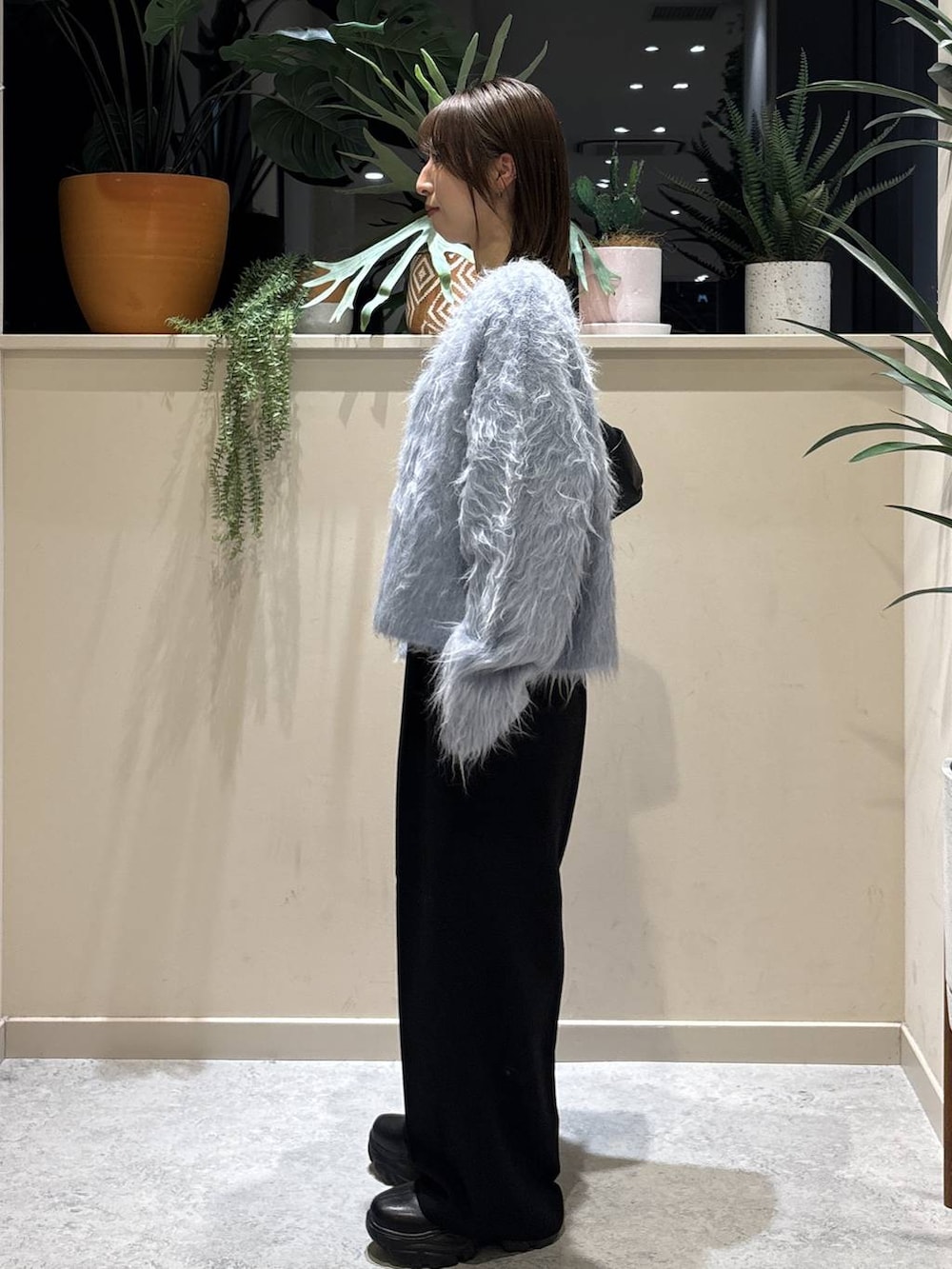 ブラック系のブーツ、ブラック系のショルダーバッグ、ブルー系のカーディガン/ボレロを着用したレディースの冬コーディネートの2枚目の写真