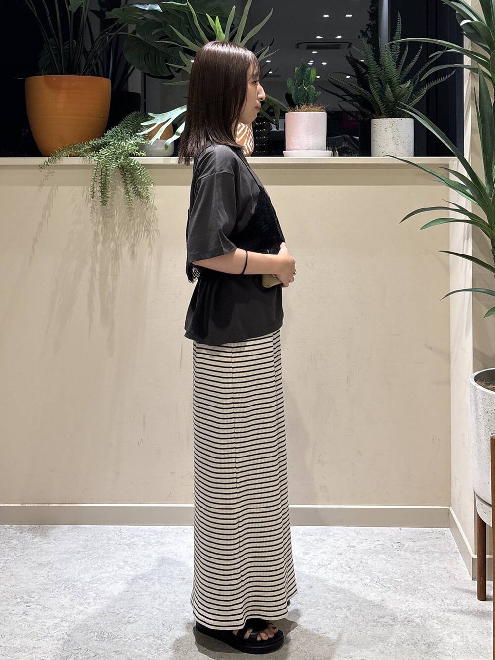 グレー系のTシャツ/カットソー、ブラック系のサンダル、ホワイト系のスカートを着用したレディースの夏コーディネートの4枚目の写真