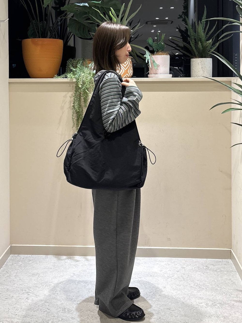 グレー系のスウェットパンツ、ブラック系のローファー、ブラック系のトートバッグを着用したレディースの春コーディネートの4枚目の写真