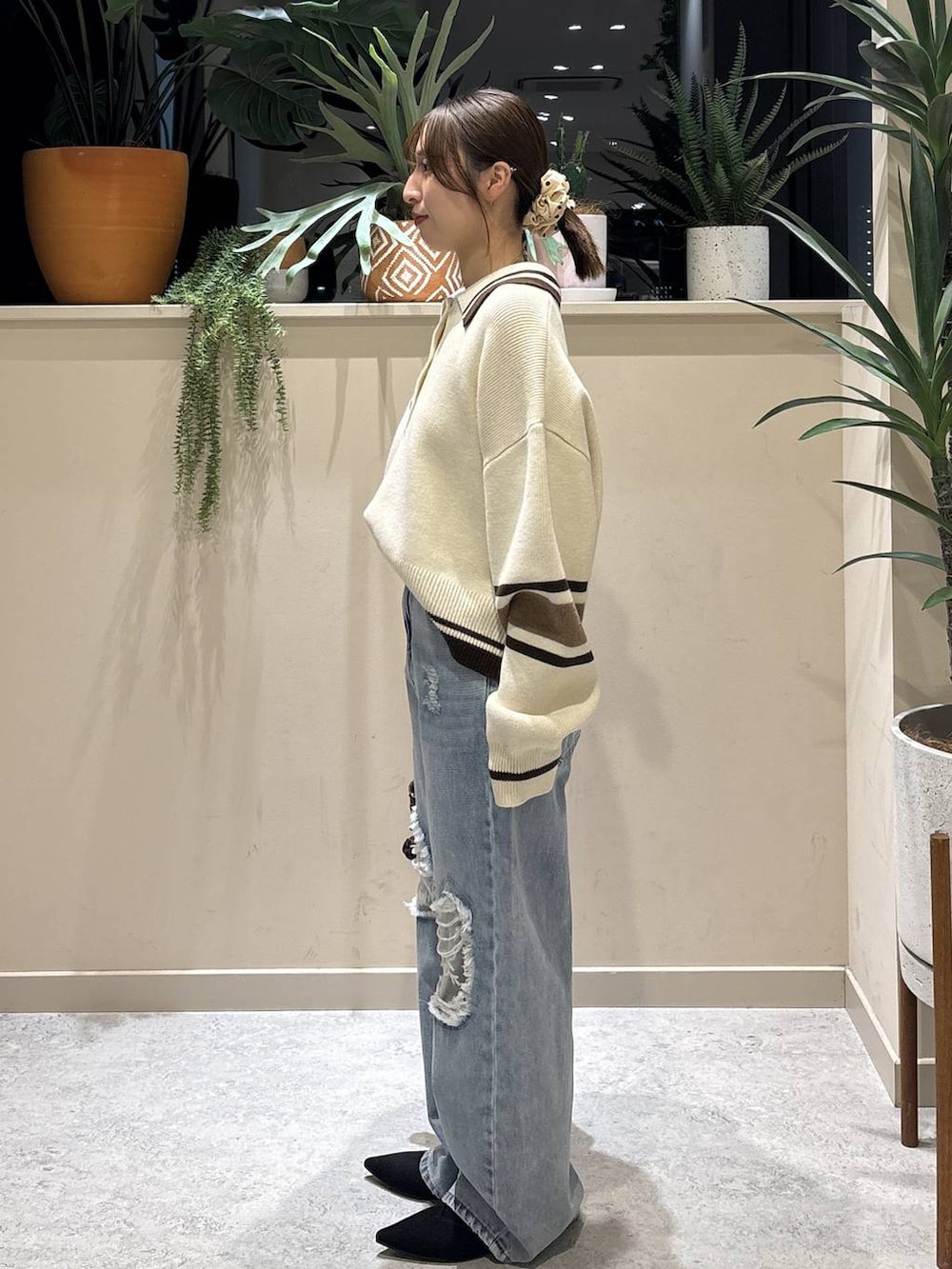 ブラウン系のボストンバッグ、ブルー系のデニムパンツ、ブラック系のパンプスを着用したレディースの冬コーディネートの2枚目の写真