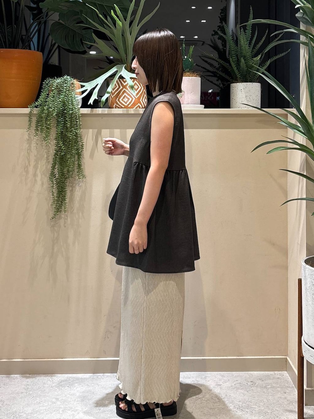 ブラック系のサンダル、ベージュ系のスカート、グレー系のベストを着用したレディースの夏コーディネートの2枚目の写真