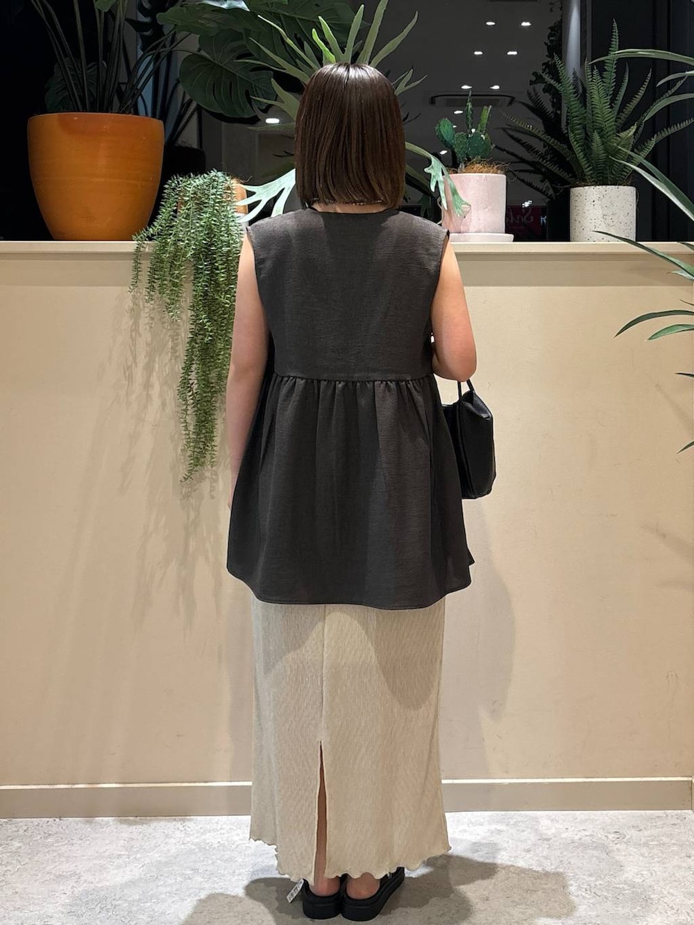 ブラック系のサンダル、ベージュ系のスカート、グレー系のベストを着用したレディースの夏コーディネートの3枚目の写真