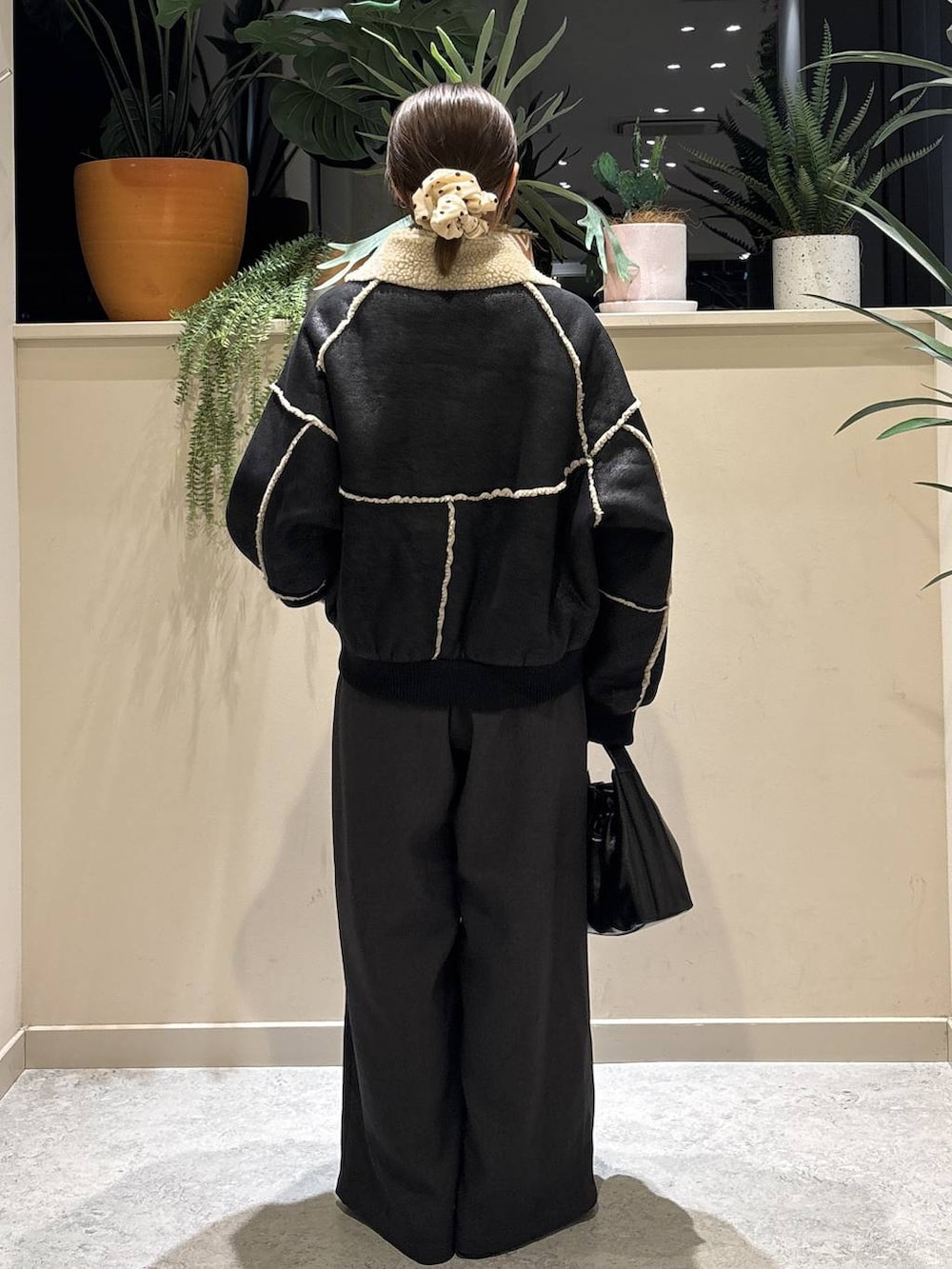 ブラック系のブルゾン、レッド系のニット/セーター、ブラック系のブーツを着用したレディースの冬コーディネートの3枚目の写真