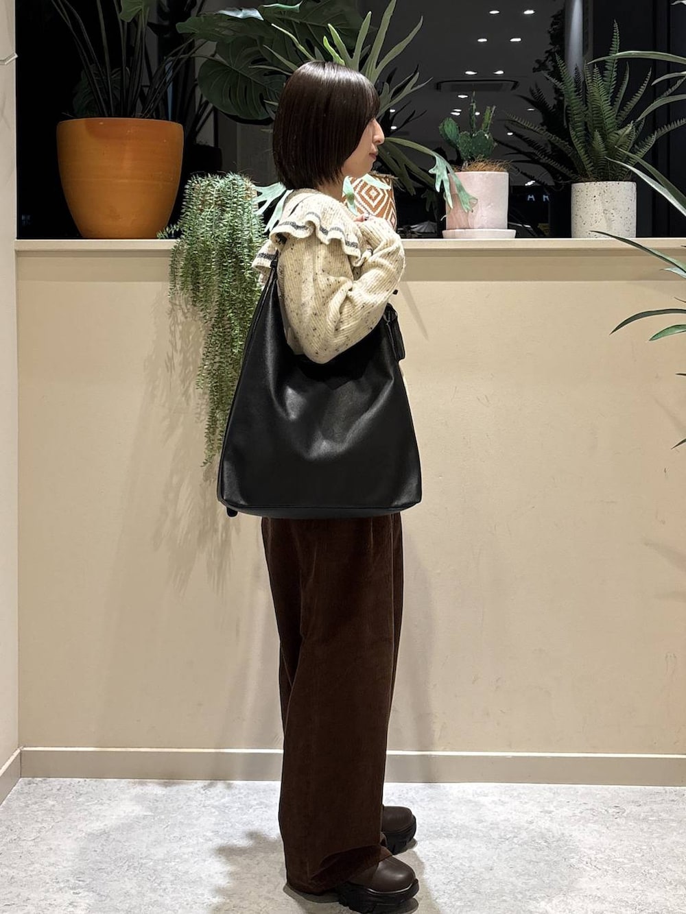 ブラック系のショルダーバッグ、ブラウン系のブーツ、ブラウン系のその他パンツを着用したレディースの秋コーディネートの3枚目の写真