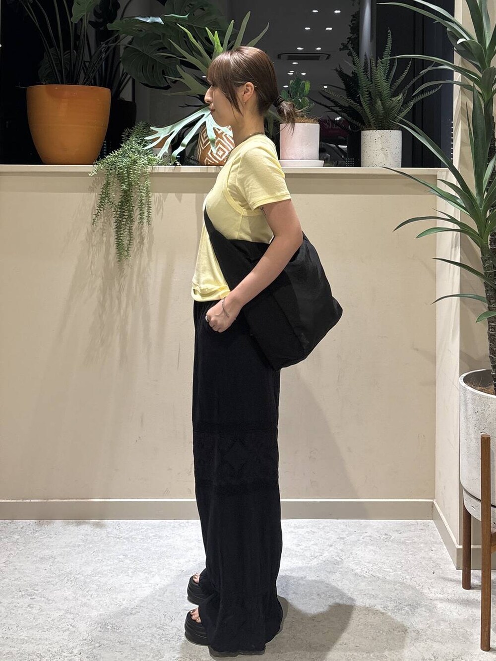 ブラック系のショルダーバッグ、イエロー系のTシャツ/カットソー、ブラック系のその他パンツを着用したレディースの夏コーディネートの2枚目の写真