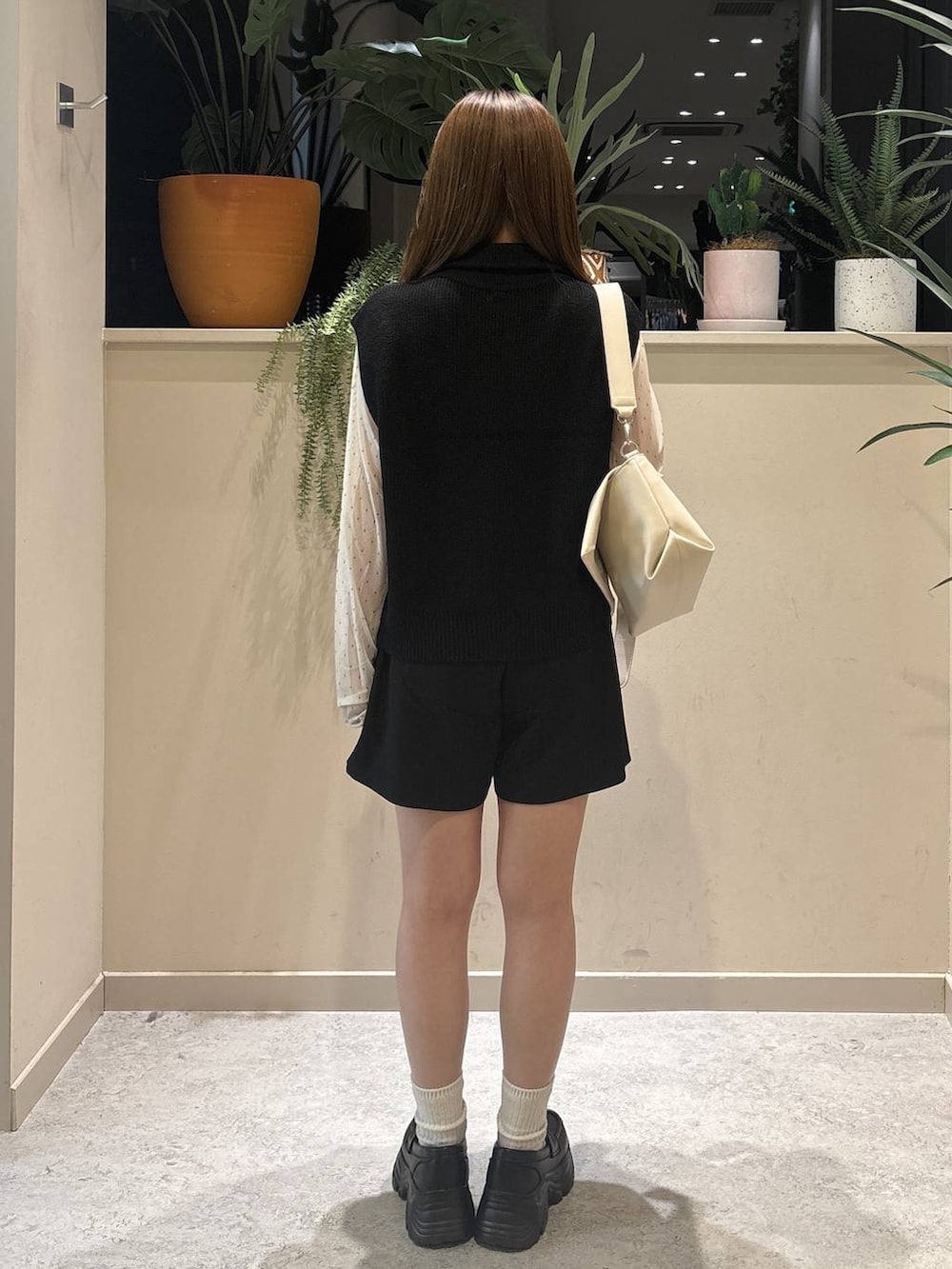 ホワイト系のショルダーバッグ、ブラック系のベスト、ホワイト系のTシャツ/カットソーを着用したレディースの秋コーディネートの3枚目の写真
