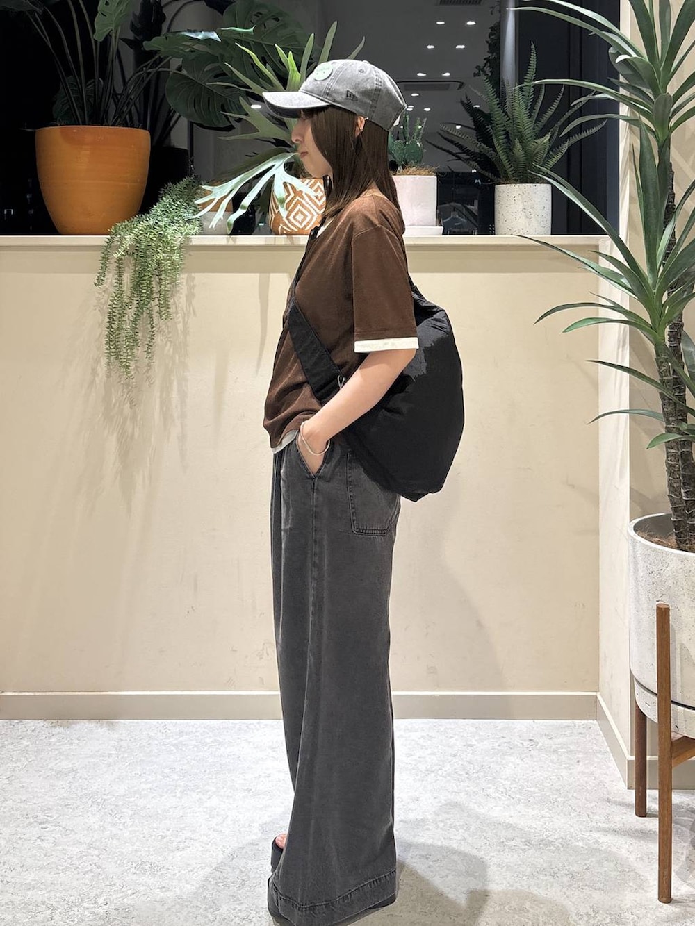 ブラック系のデニムパンツ、ブラック系のサンダル、ブラウン系のTシャツ/カットソーを着用したレディースの夏コーディネートの2枚目の写真