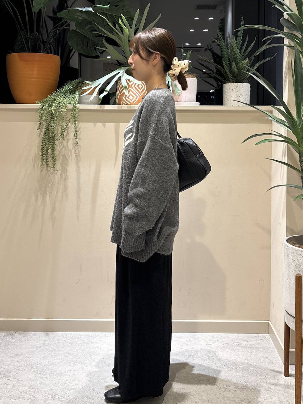 ブラック系のスカート、ブラック系のブーツ、ブラック系のボストンバッグを着用したレディースの冬コーディネートの2枚目の写真