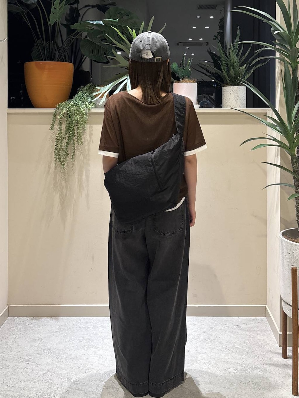 ブラック系のデニムパンツ、ブラック系のサンダル、ブラウン系のTシャツ/カットソーを着用したレディースの夏コーディネートの3枚目の写真