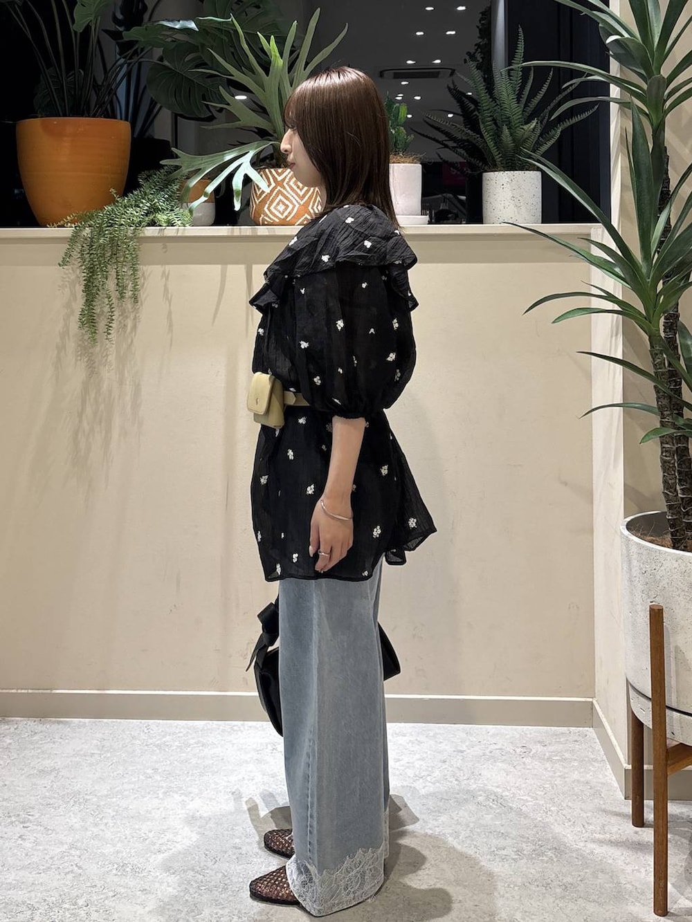 ブラック系のワンピース、ブルー系のデニムパンツ、ブラック系のショルダーバッグを着用したレディースの夏コーディネートの2枚目の写真