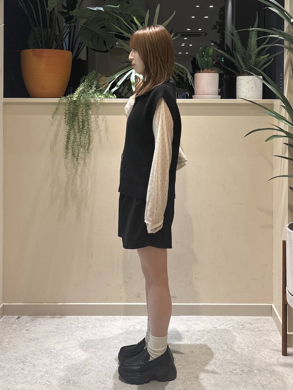 ホワイト系のショルダーバッグ、ブラック系のベスト、ホワイト系のTシャツ/カットソーを着用したレディースの秋コーディネートの2枚目の写真