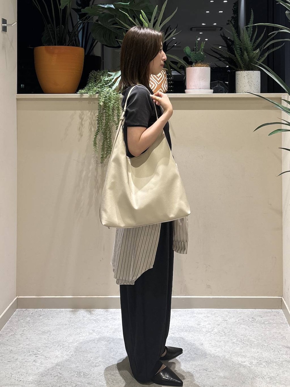 ホワイト系のショルダーバッグ、グレー系のTシャツ/カットソー、ブラック系のその他パンツを着用したレディースの春コーディネートの4枚目の写真