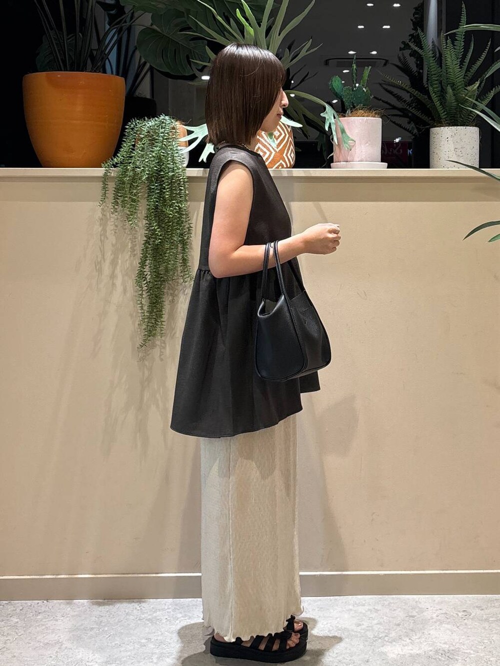 ブラック系のサンダル、ベージュ系のスカート、グレー系のベストを着用したレディースの夏コーディネートの4枚目の写真