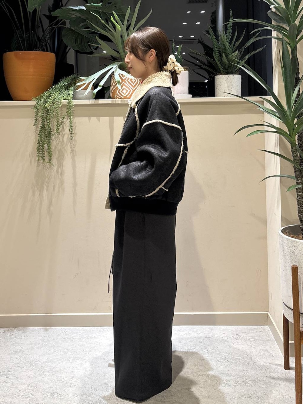 ブラック系のブルゾン、レッド系のニット/セーター、ブラック系のブーツを着用したレディースの冬コーディネートの2枚目の写真