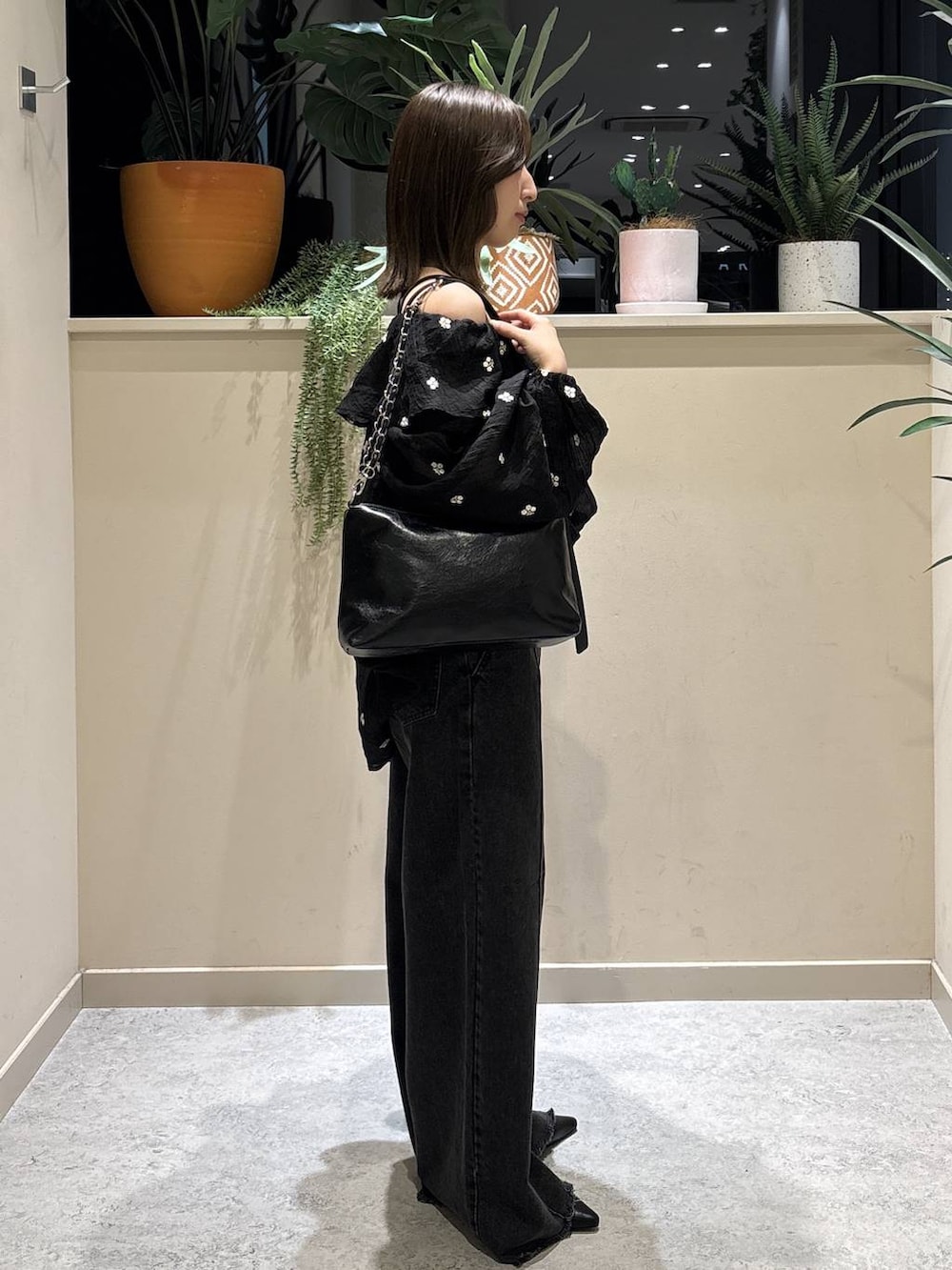ブラック系のショルダーバッグ、ブラック系のデニムパンツ、ブラック系のサンダルを着用したレディースの春コーディネートの4枚目の写真