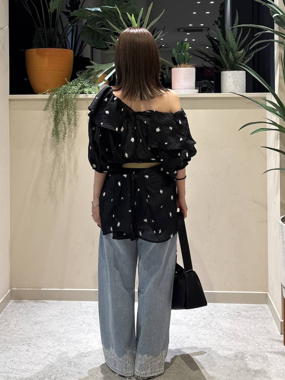 ブラック系のワンピース、ブルー系のデニムパンツ、ブラック系のショルダーバッグを着用したレディースの夏コーディネートの3枚目の写真