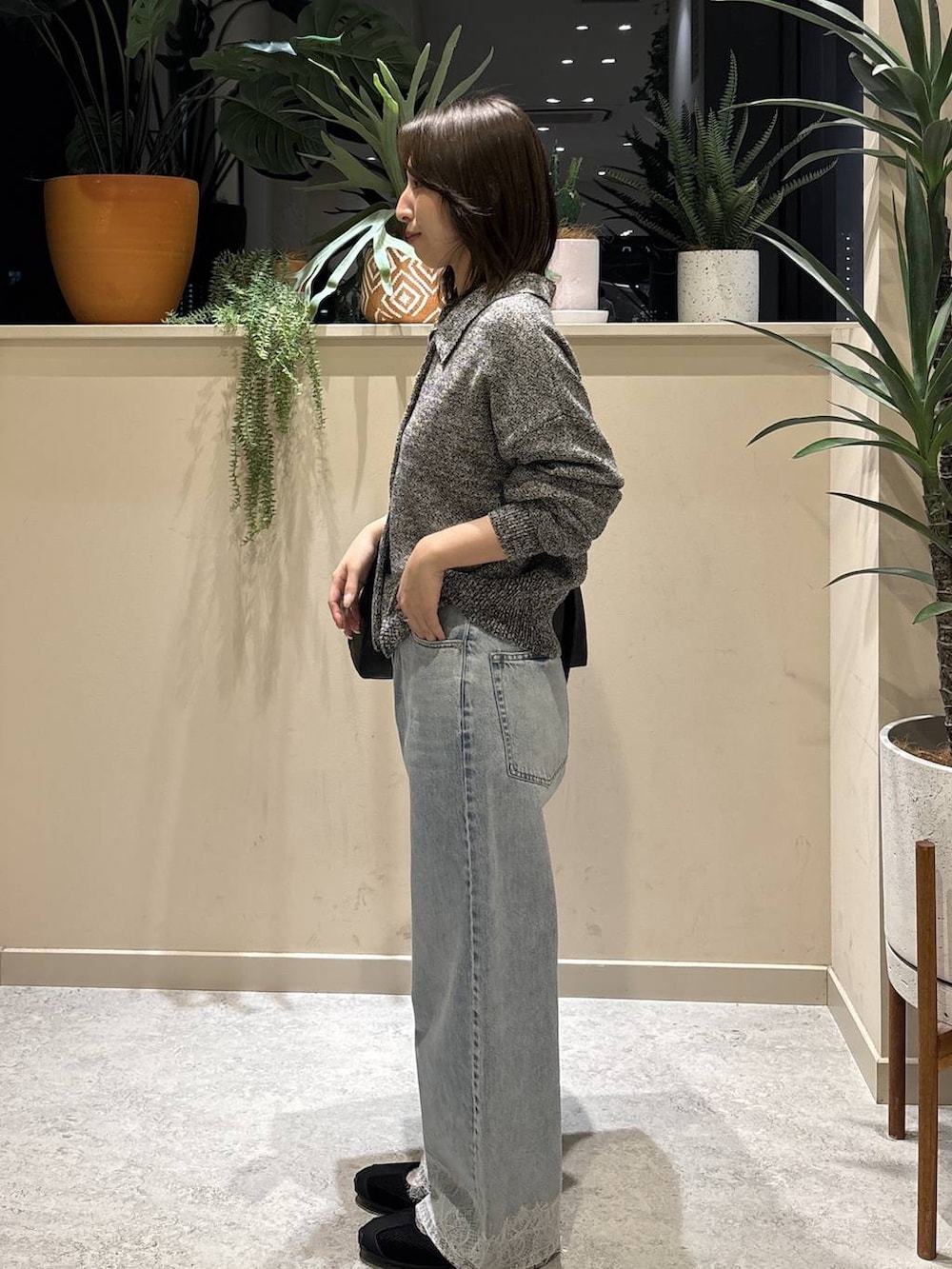 ブラック系のショルダーバッグ、ブルー系のデニムパンツ、ブラック系のスニーカーを着用したレディースの春コーディネートの2枚目の写真